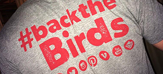 Back of male student's tshirt that says '#BacktheBirds'