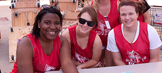 Three female student helpers sitting at table outside during move-in